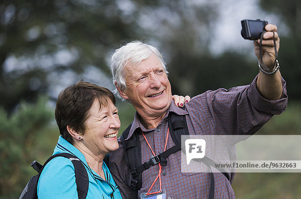 A mature couple taking a selfy photograph while out walking.