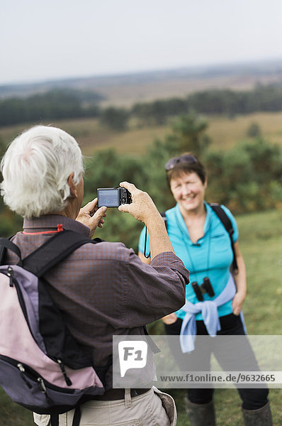 A mature couple taking photographs while out walking.