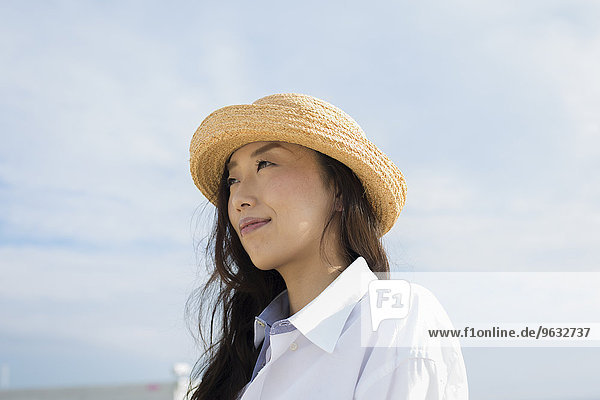 A woman in a straw hat on a beach in Kobe.
