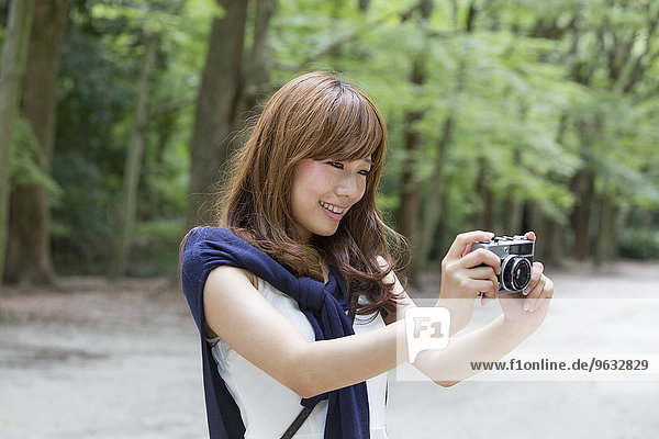 A woman in a Kyoto park holding a camera  preparing to take pictures.
