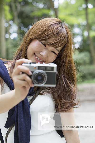 A woman in a Kyoto park holding a camera  preparing to take pictures.
