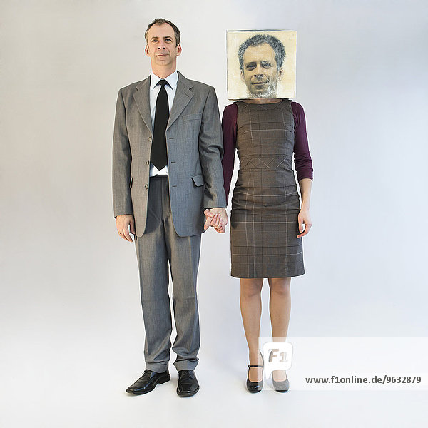 Businessman holding hands and standing near businesswoman wearing mask