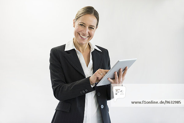 Portrait of businesswoman in black suit using digital tablet  smiling