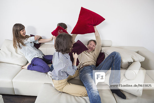Family doing pillow fight on couch