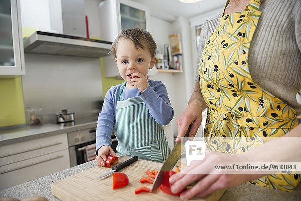 Son nibbling vegetables while mother is cutting them