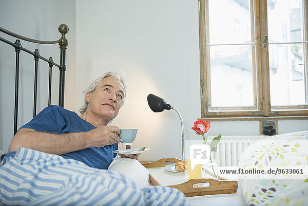 Mature man having breakfast in bed