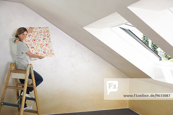 Woman ladder sitting holding wallpaper pattern