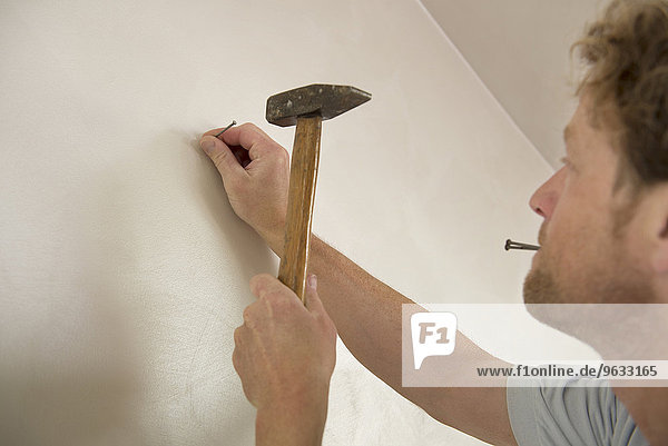 Man hammer nail wall portrait close-up