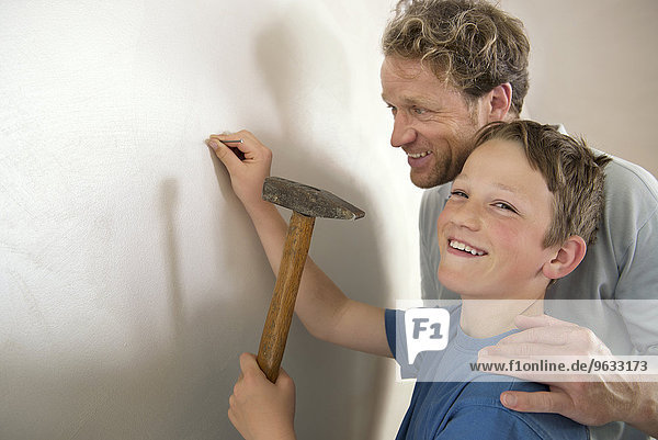 Smiling father son working together hammer wall
