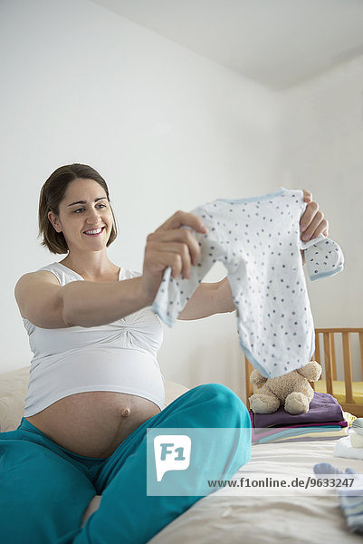 Pregnant woman holding packing baby clothes