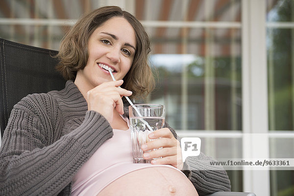 Portrait pregnant woman smiling drinking straw