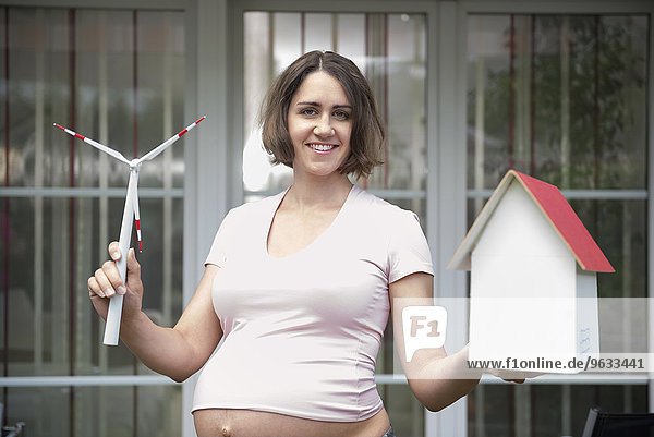 Pregnant woman holding model windmill model house