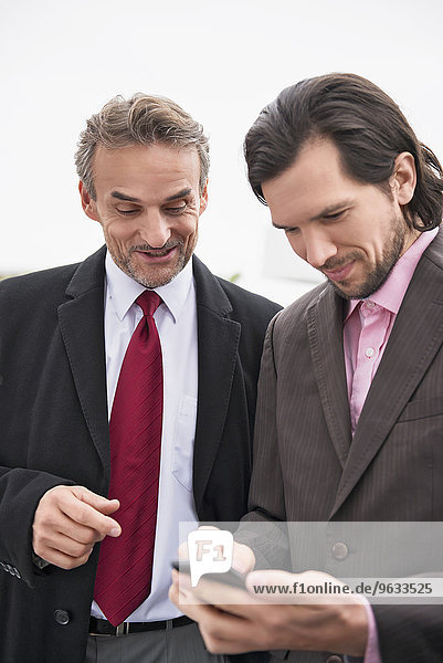 Two businessmen talking phone planning online