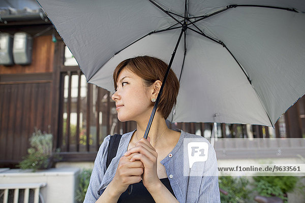 Woman standing outdoors  holding an umbrella.
