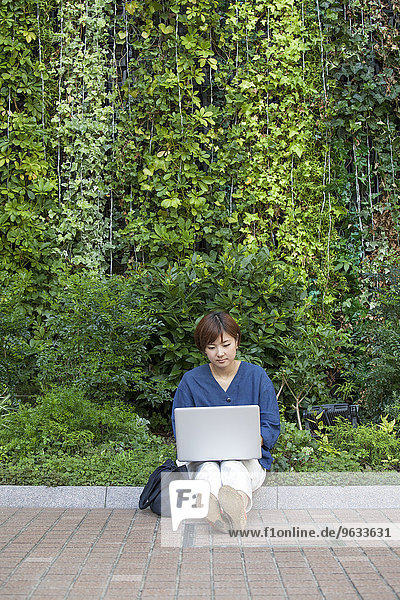 A woman with a laptop sitting outdoors.