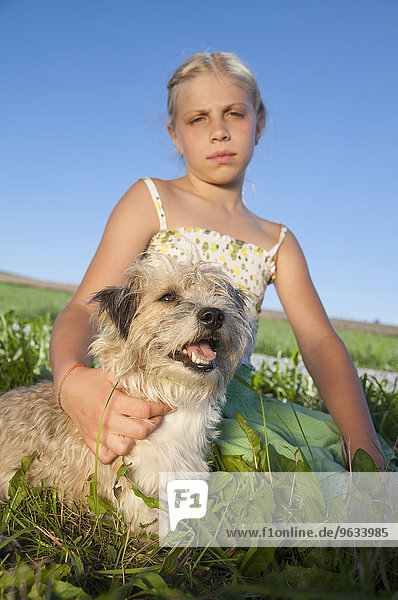 Girl (10-11) sitting with dog in meadow  portrait