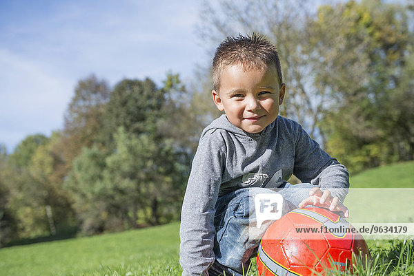 Portrait small boy red football meadow smiling