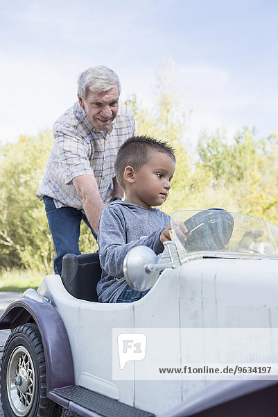 Grandson driving vintage model car grandfather