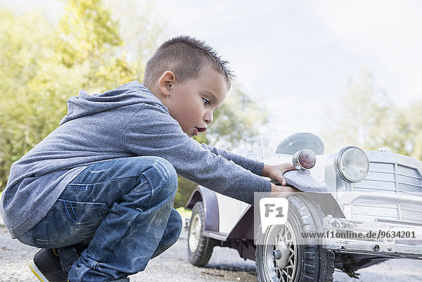 Boy checking wheel model toy vintage car