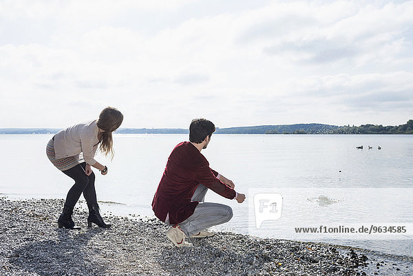 Young couple lake skimming stones