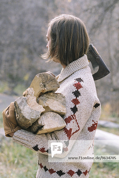 Young blond man carrying firewood.