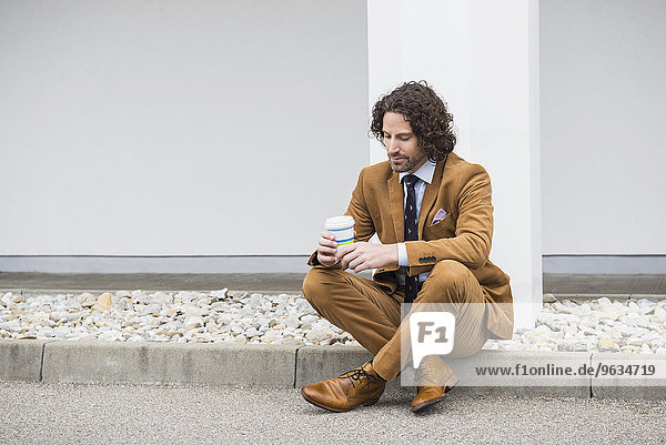 Worried businessman sitting Coffee to go roadside