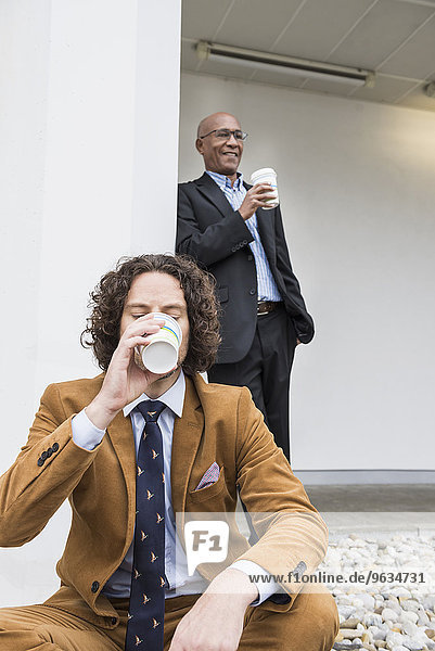 Two businessmen drinking coffee taking break