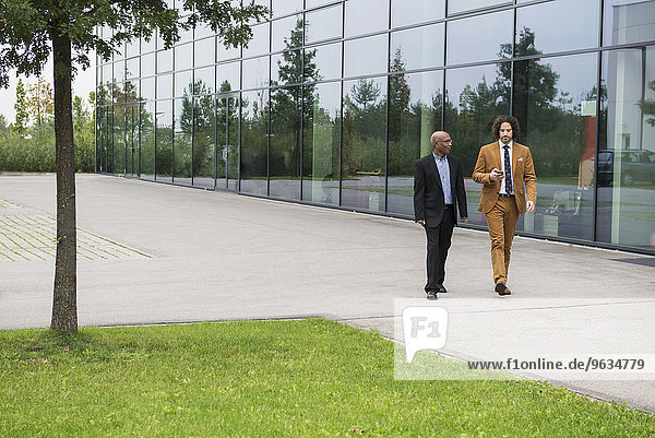 Two businessmen walking talking African Caucasian