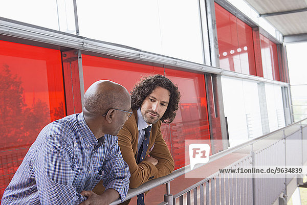 Two men meeting talking African Caucasian railing