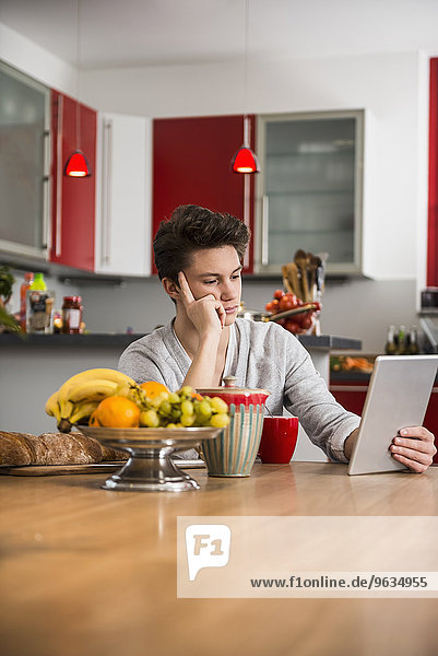 Young man looking at digital tablet in kitchen table