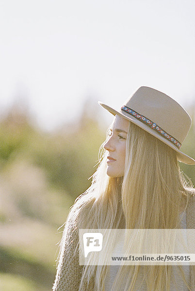 An apple orchard in Utah. Portrait of a woman with long blond hair  wearing a hat.