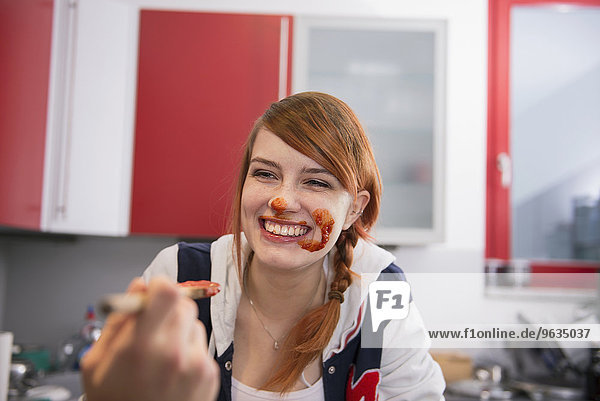 Happy young woman got messy while eating tomato ketchup