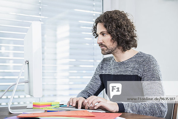 Businessman sitting at desk working on computer in office