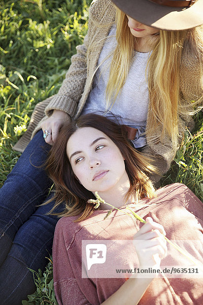 An apple orchard in Utah. Two women lying in the grass.