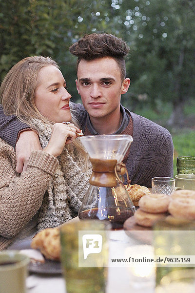 An apple orchard in Utah. A couple embracing  food and drink on a table.
