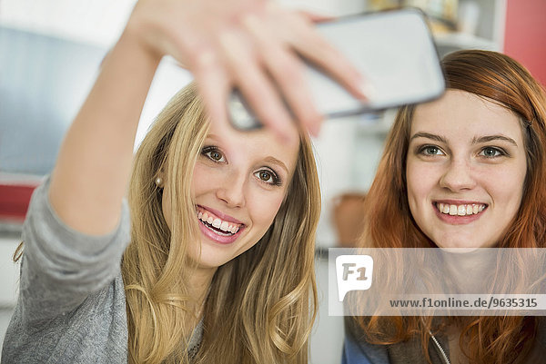 Happy girl friends taking a selfie with smartphone