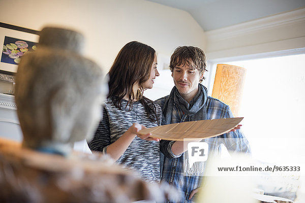 Smiling couple standing in a living room  woman holding a wooden tray.