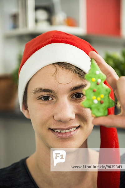 Portrait of a young man showing Christmas tree cookie