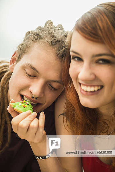 Young woman feeding cookie to her friend