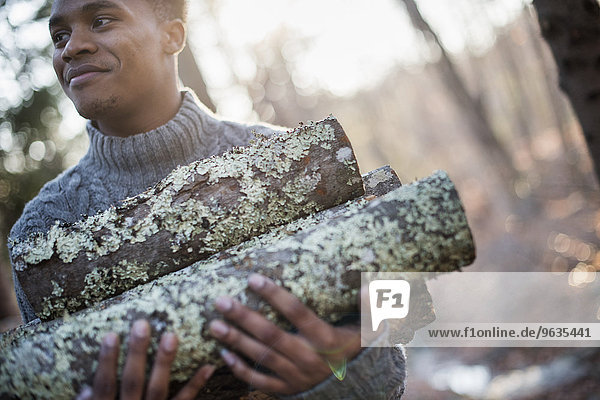 Man carrying firewood in forest in autumn.