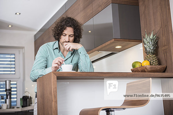 Man drinking cup of coffee in a kitchen