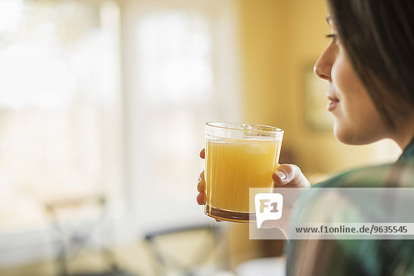 A woman holding a glass of orange juice.