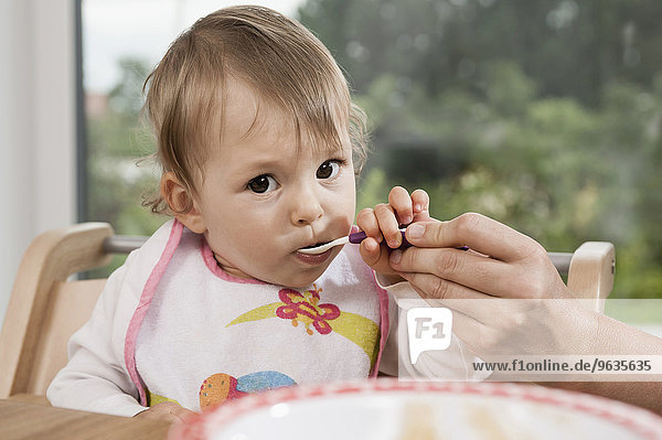 Portrait 1 year old baby girl spoon eating
