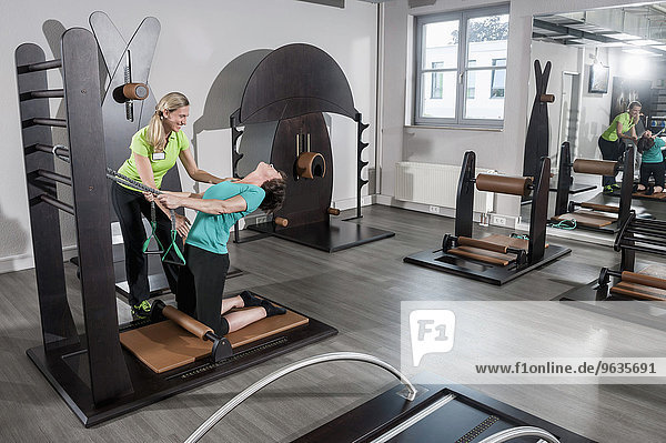 Mature woman stretching fitness studio trainer
