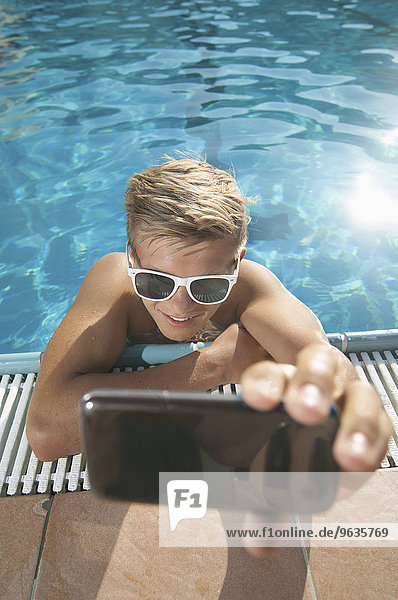 Teenager taking selfie swimming pool sunglasses