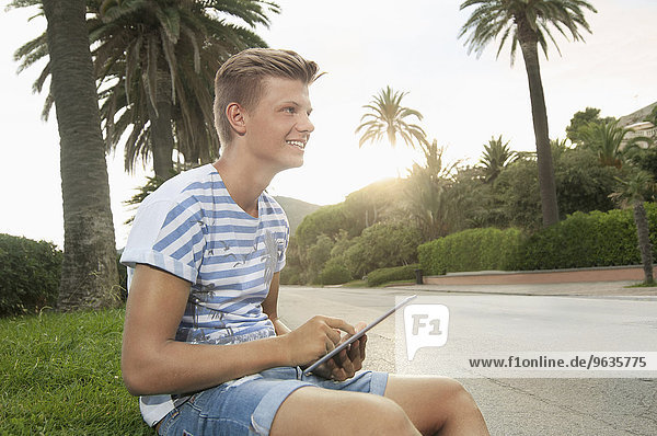 Teenage boy holding tablet computer smiling