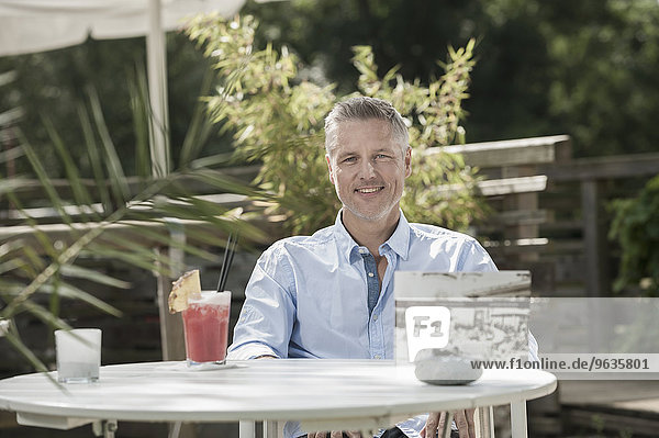 Portrait smiling man cocktail sitting table garden
