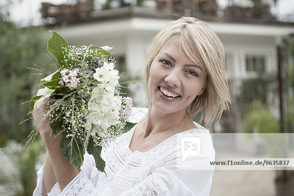 Portrait blond woman celebrating holding bouquet