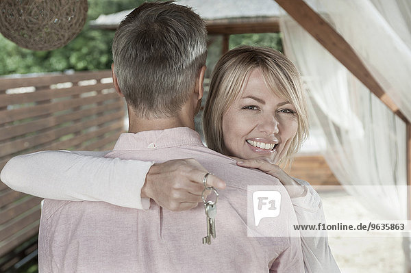 Loving couple hugging garden woman holding keys