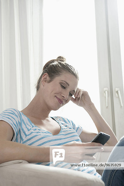 Attractive young blond pregnant woman reading SMS